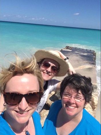 Three women posing for a selfie by the ocean.