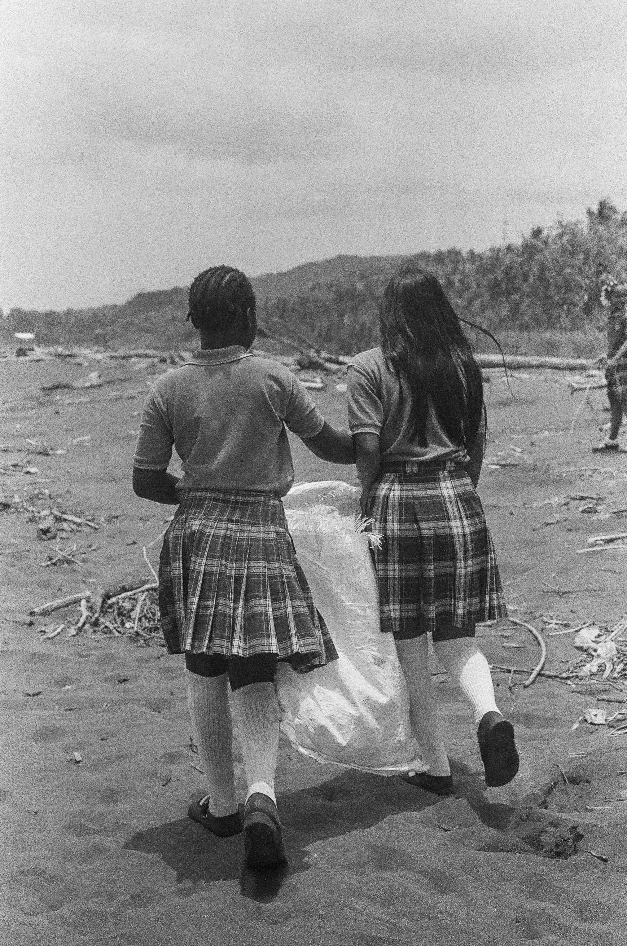 Dos estudiantes recogen basura durante la limpieza de una playa.