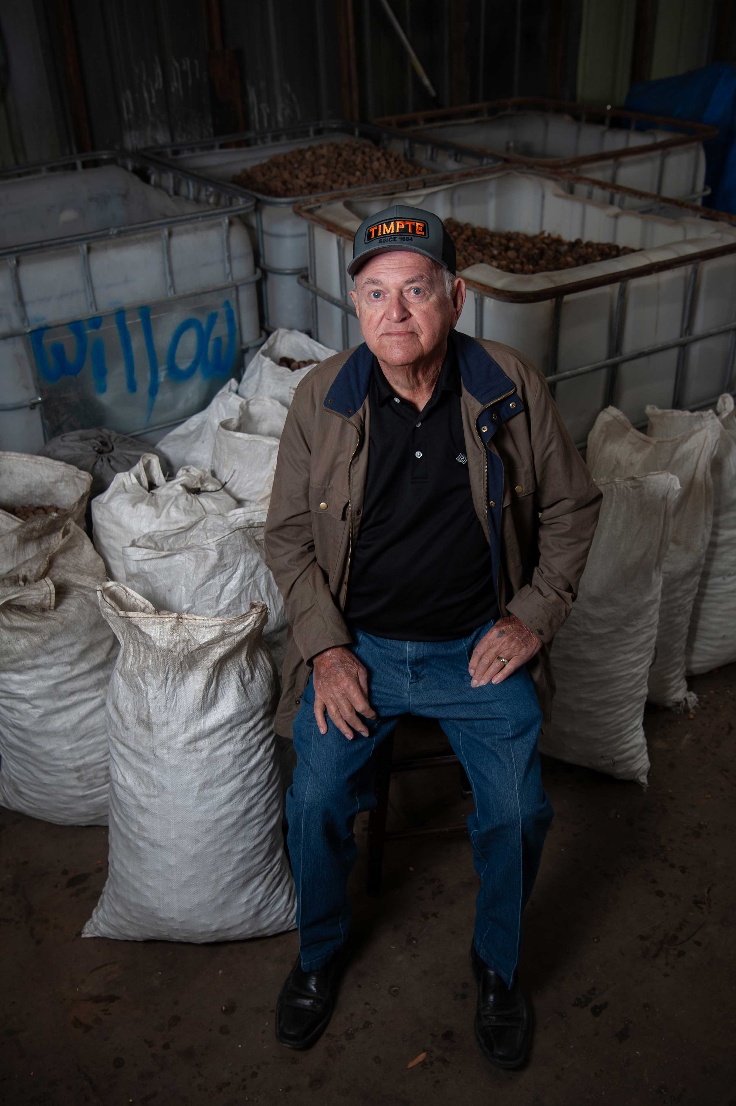 Sidney Miller sits on a stack of sacks containing acorns at his seed supply company.