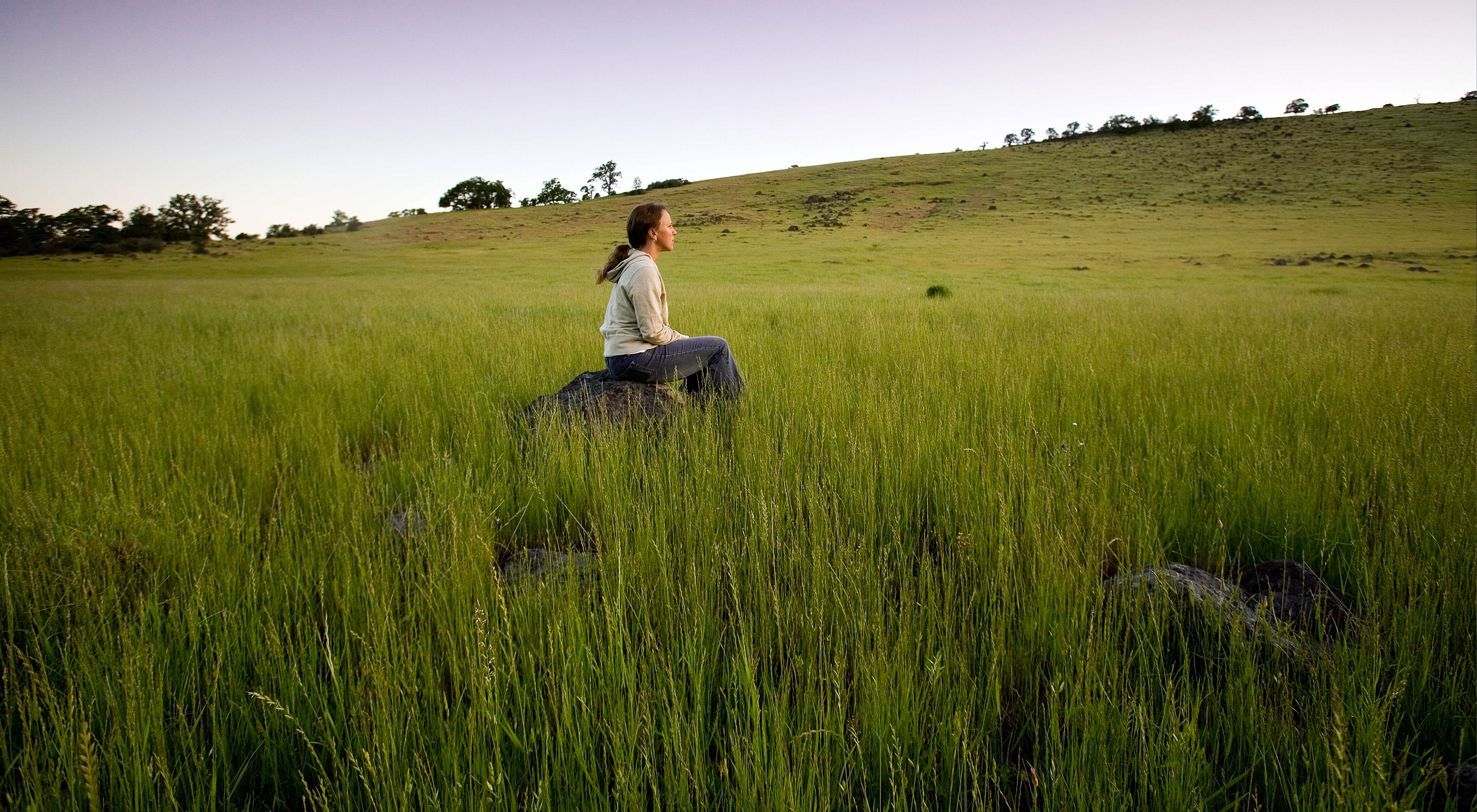 A female hiker pauses to view the lush grasslands
